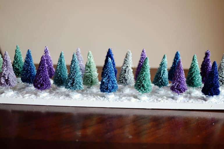 Turn some typical bottle brush trees, found at your local dollar store, into this whimical Christmas scene with just a few crafty supplies!