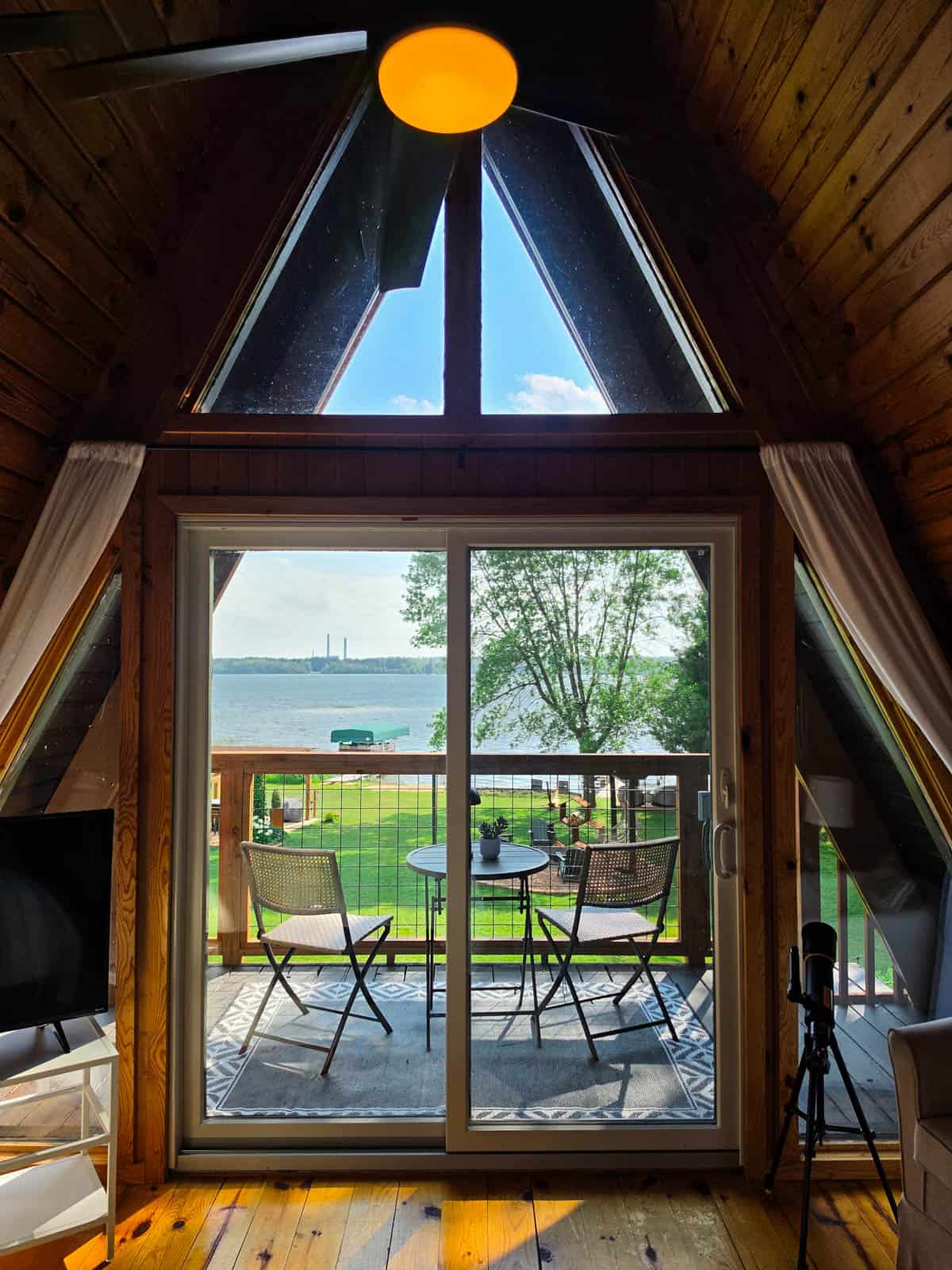 View through A-frame bedroom windows to private balcony and Bass Lake