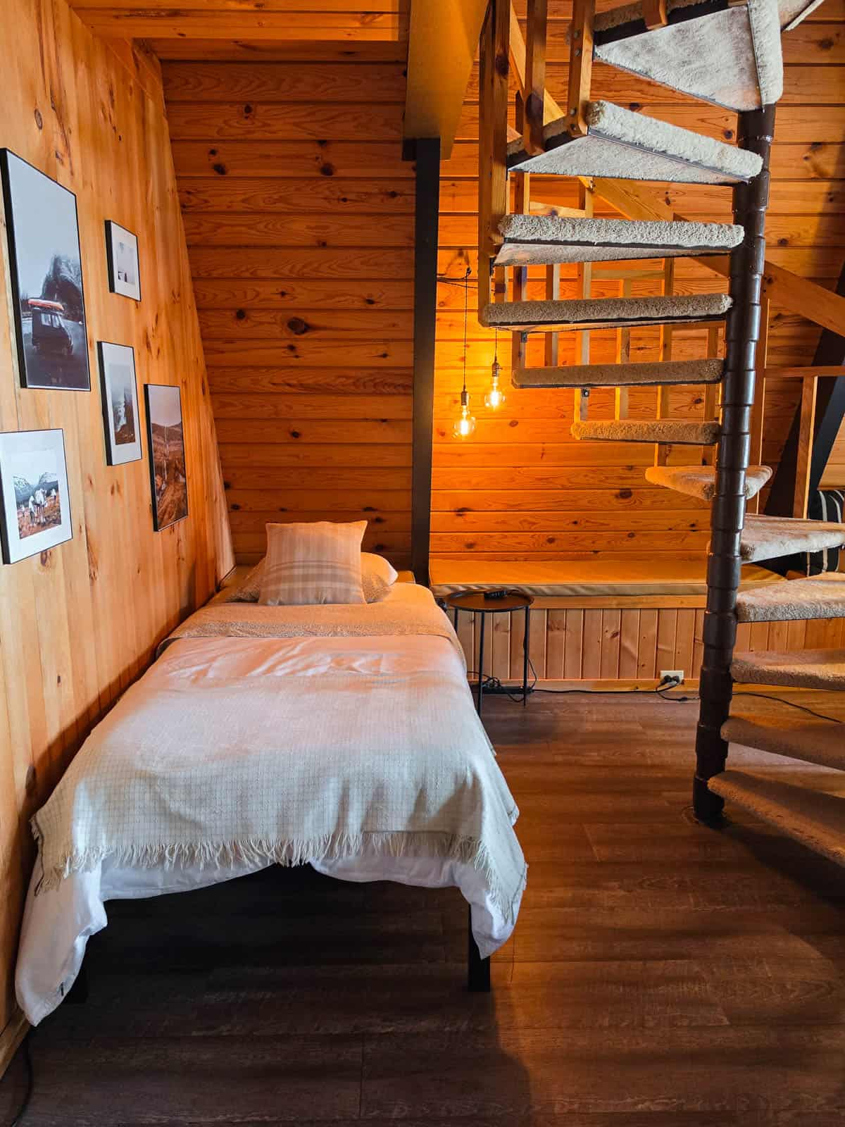 Downstairs bed beside the spiral staircase inside the A-frame cabin