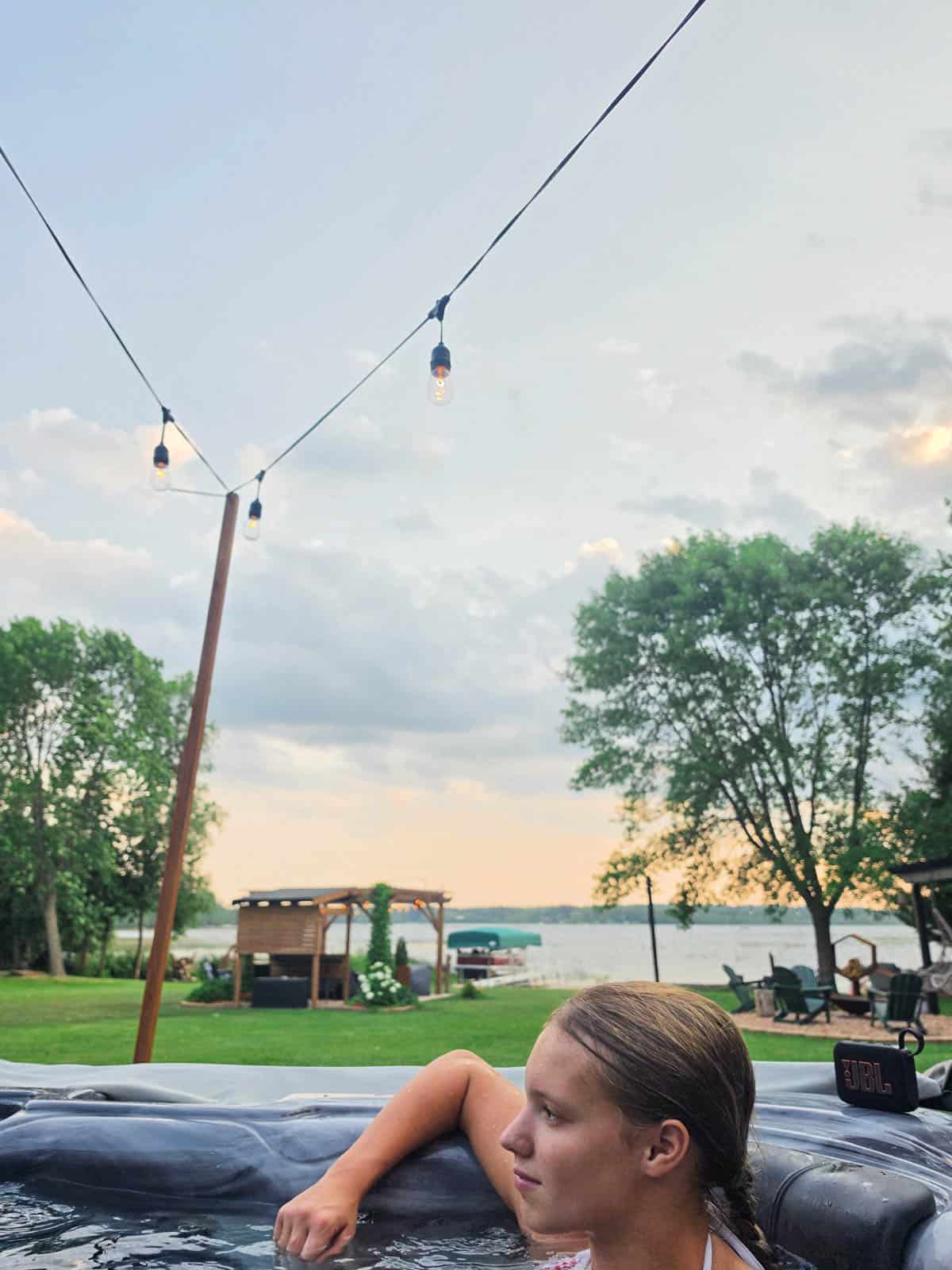 Person relaxing in the hot tub overlooking Bass Lake at the A-frame cabin