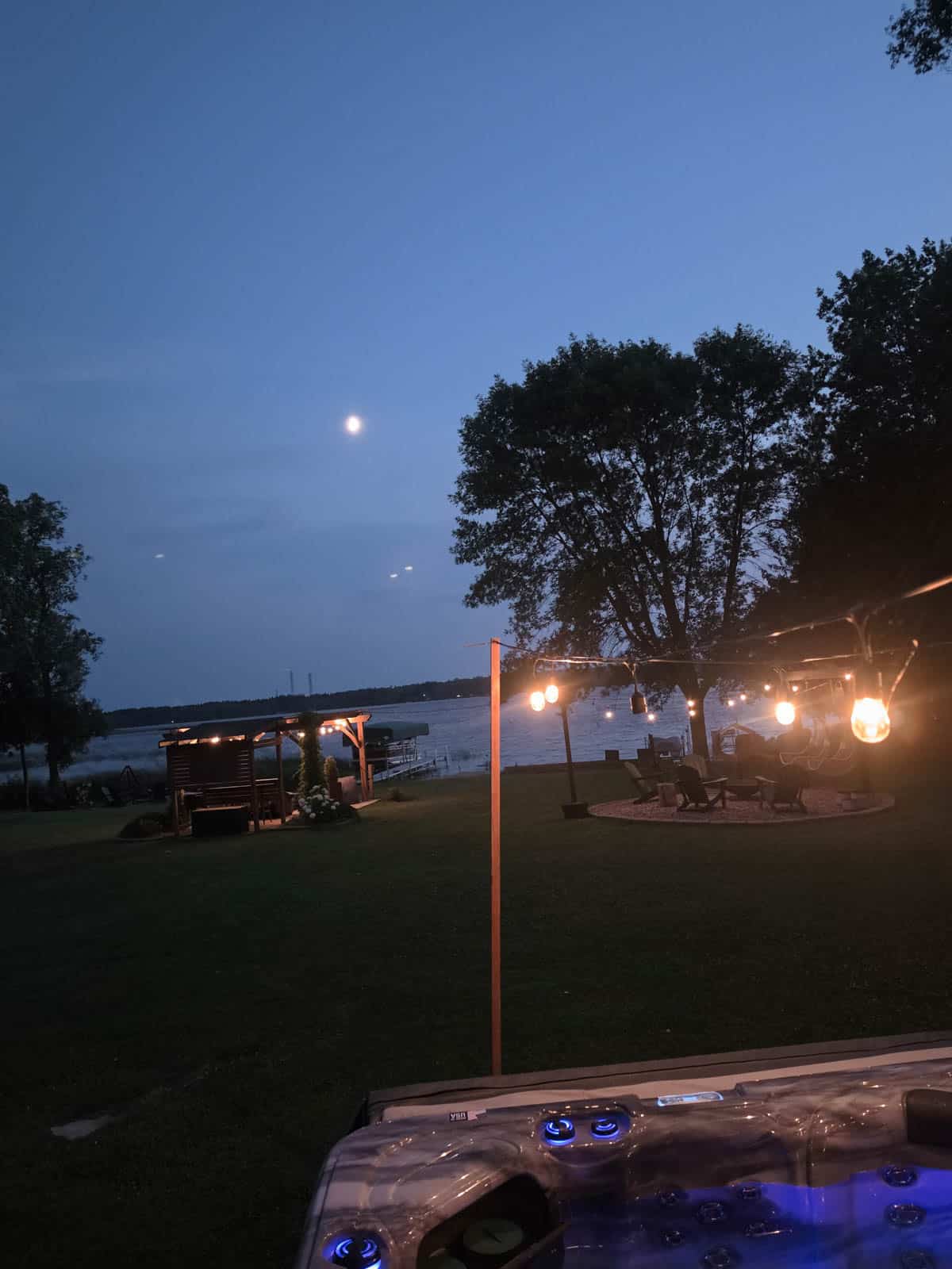 Hot tub overlooking Bass Lake at dusk with string lights and moonlight