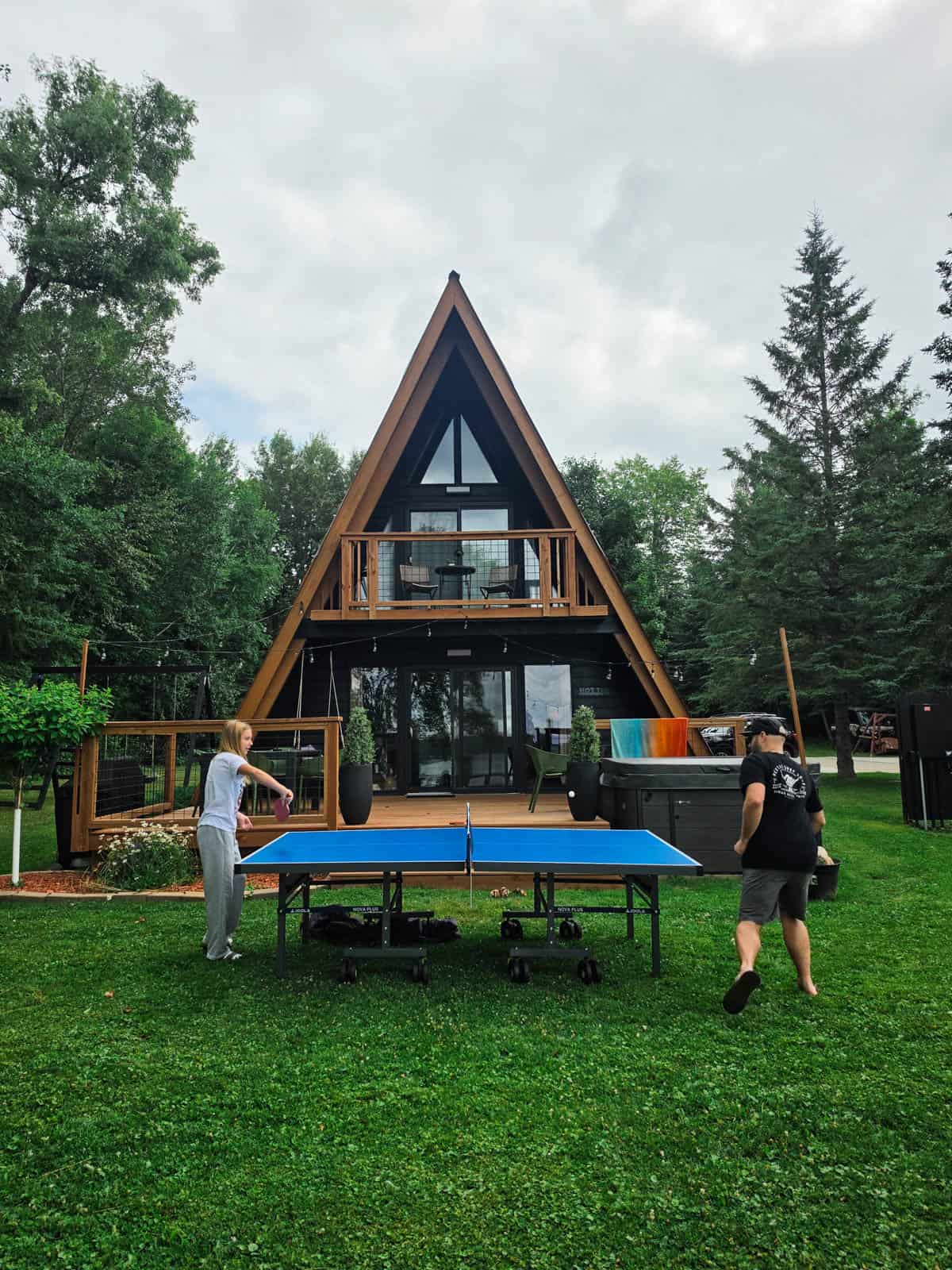 Family playing ping pong outside a Minnesota A-frame cabin