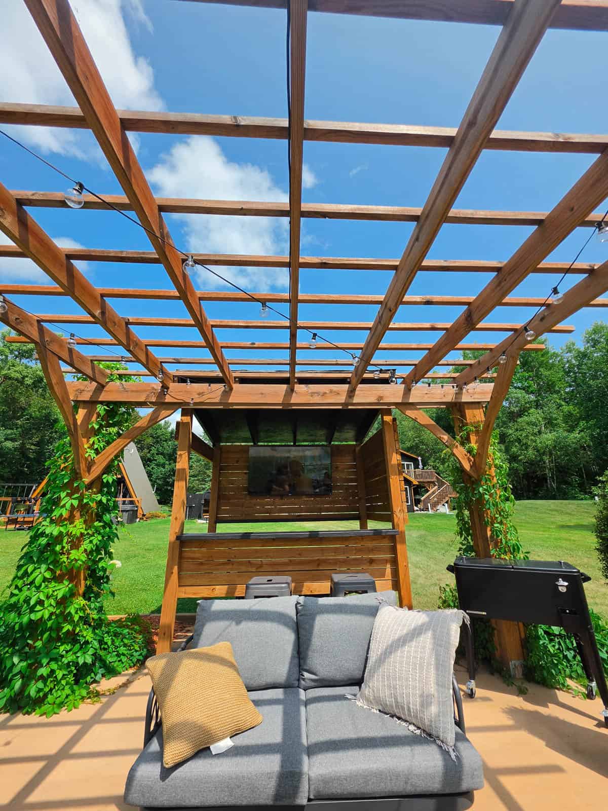 Outdoor living room at the A-frame cabin with sofa, bar area, and pergola
