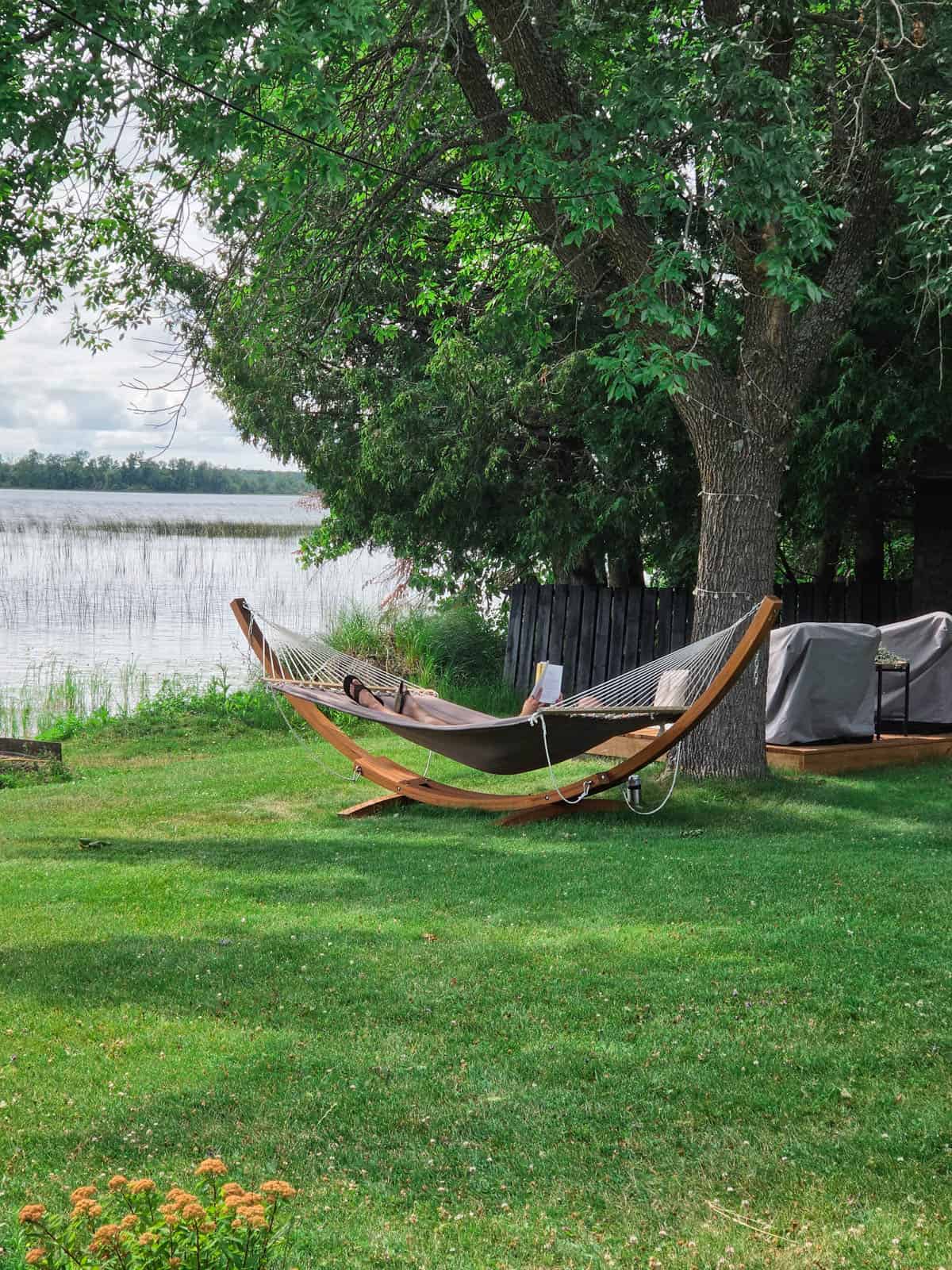 Person relaxing in a hammock beside Bass Lake at the A-frame cabin