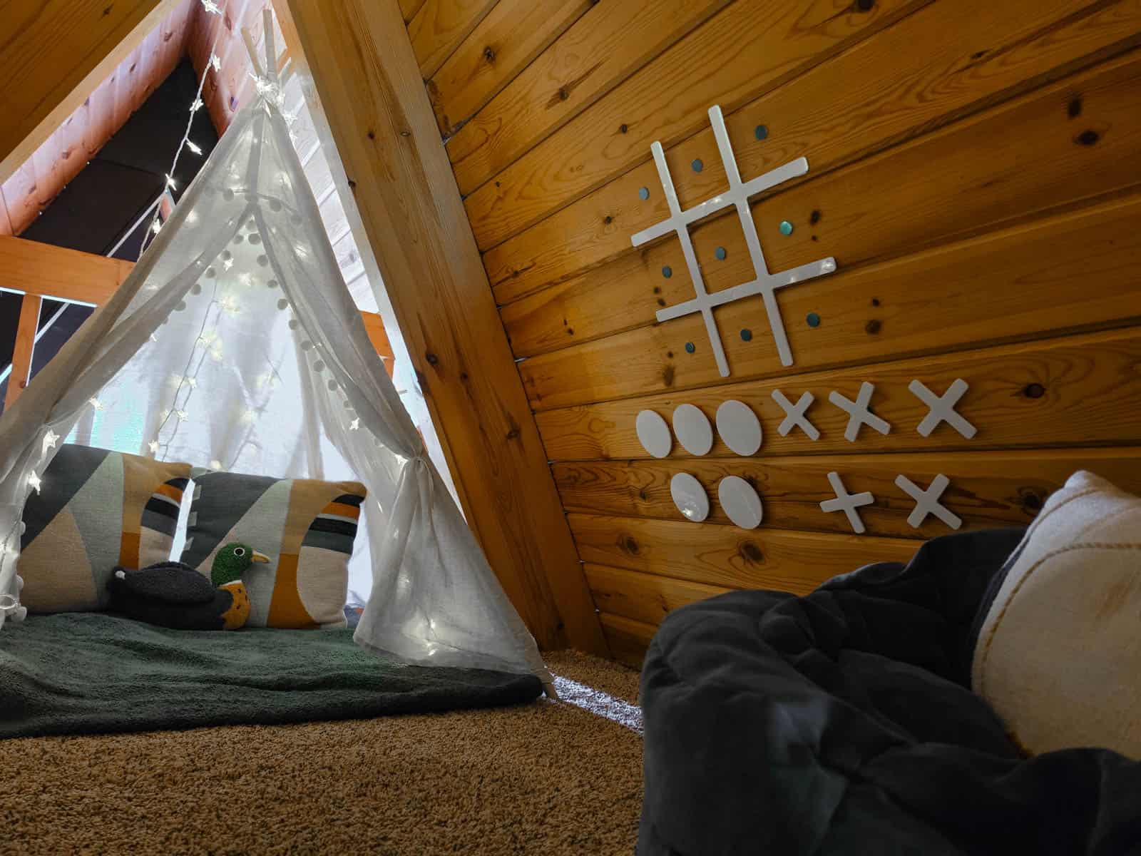 A-frame cabin loft play area with tent and tic-tac-toe wall game
