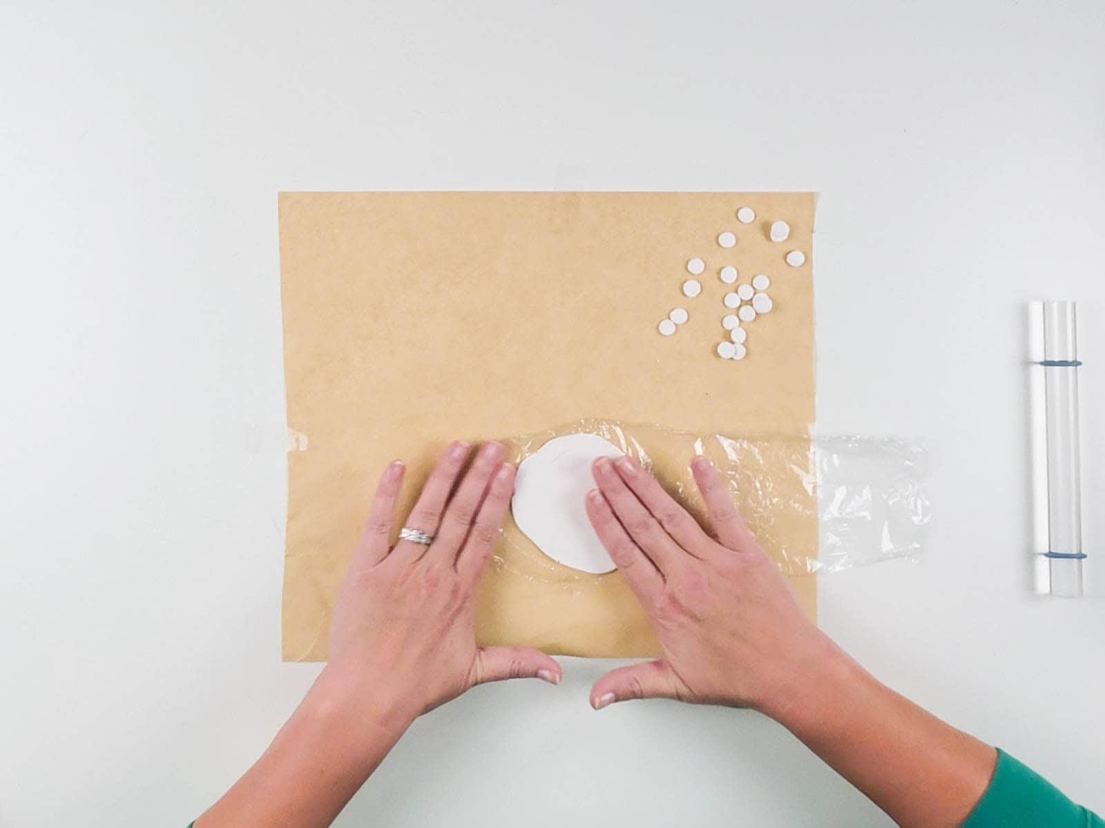Plastic wrap placed over rolled polymer clay before cutting small circles